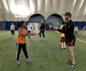 Thrive participants learning how to play rugby on an indoor field.