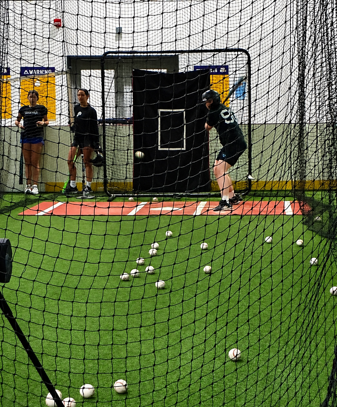 A batter practicing their swing at the baseball cages.