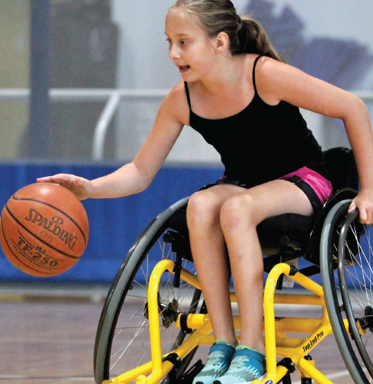 A girl dribbles the ball during a wheelchair basketball game.