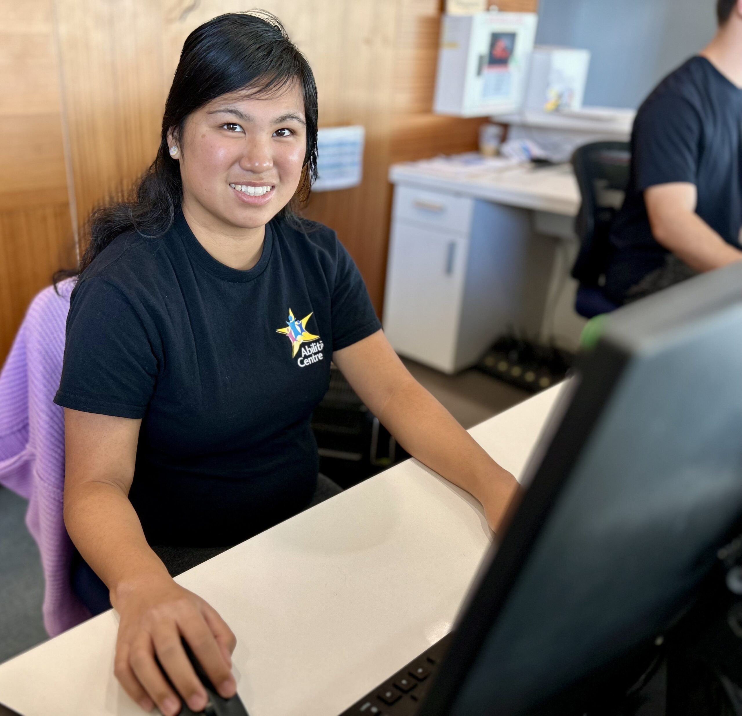 A woman smiles while working at the front desk.