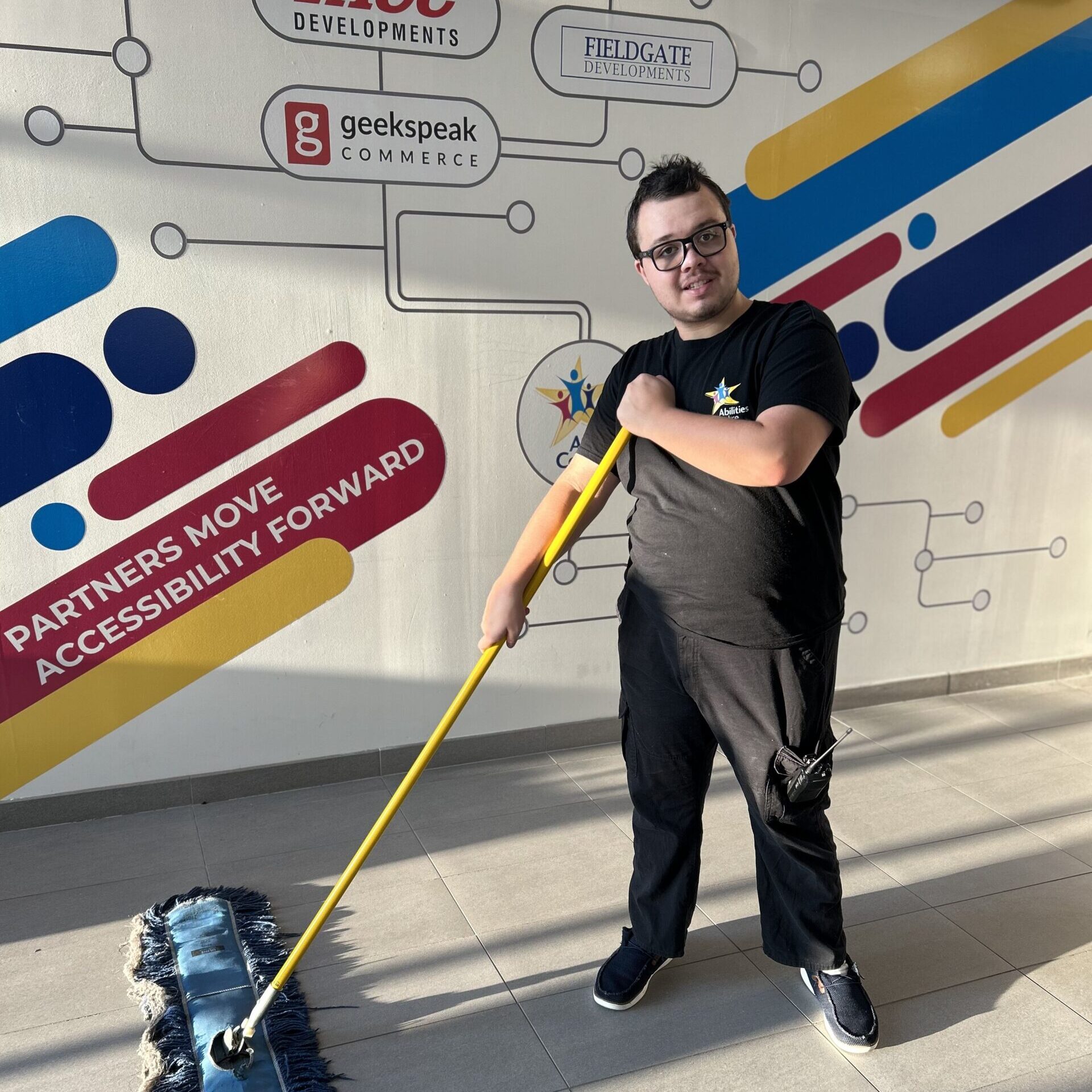 An employment participant poses while sweeping the floor.