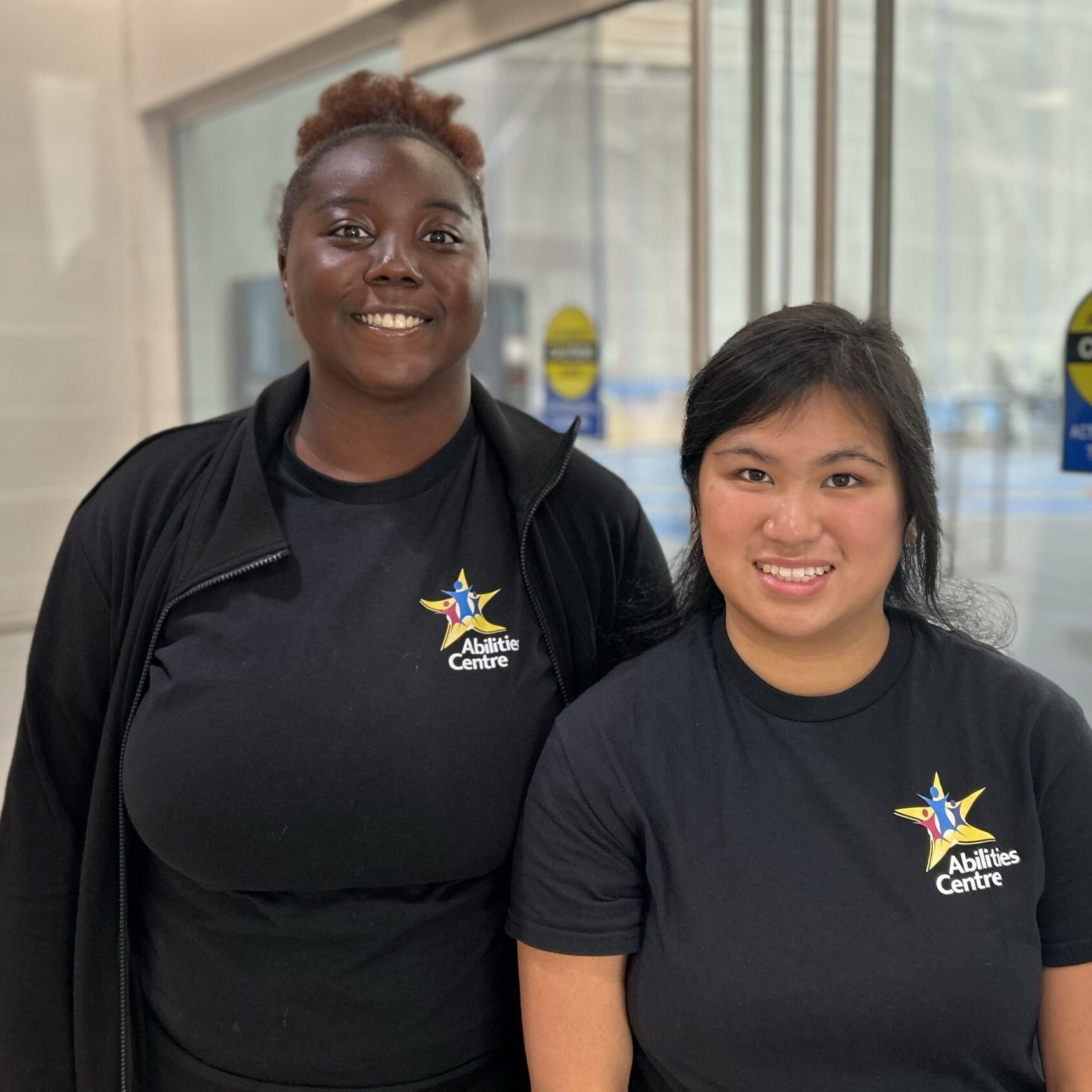 Two women post in their Abilities Centre shirts.