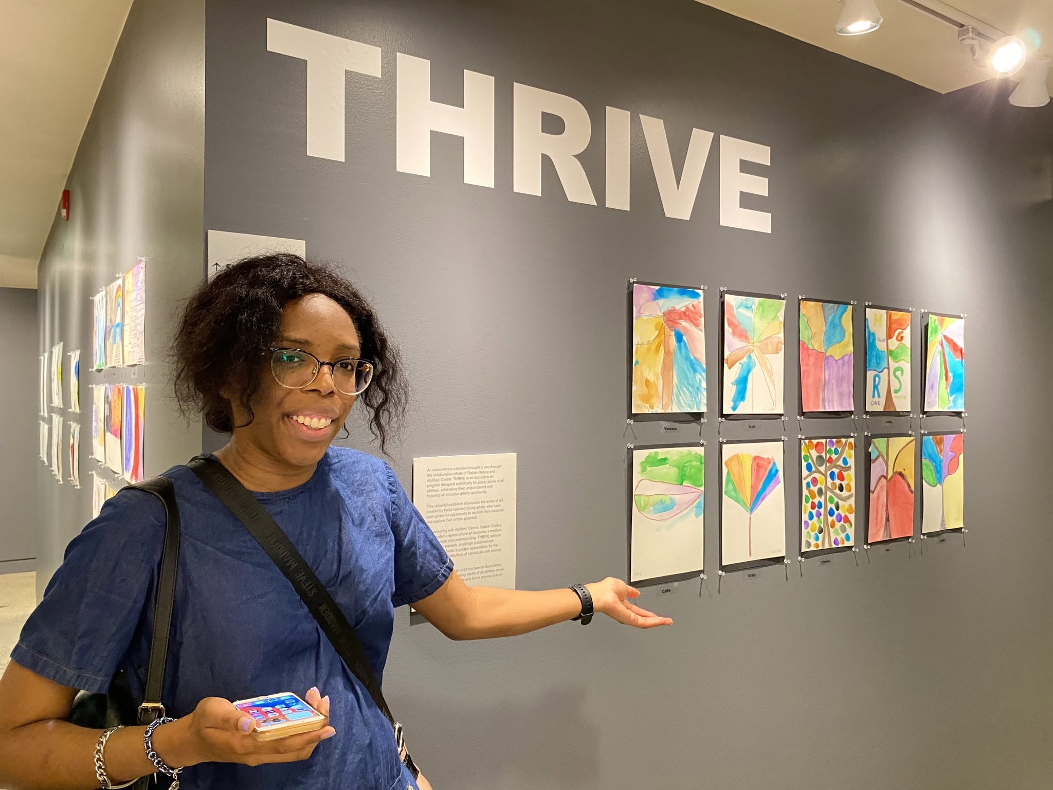 A woman showcases the artwork created by Thrive participants.