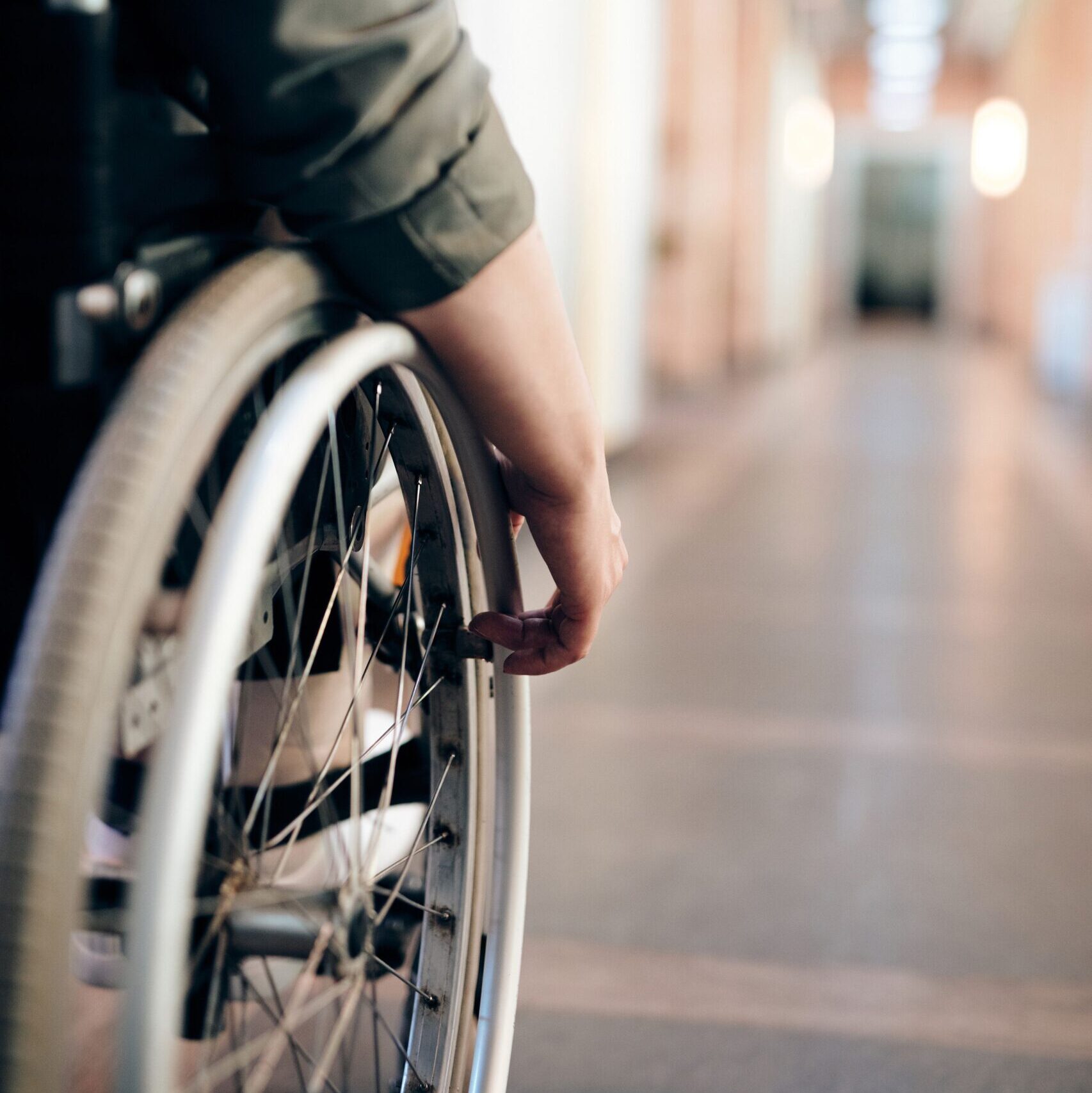 A close-up of the wheels and hand of someone who uses a wheelchair.