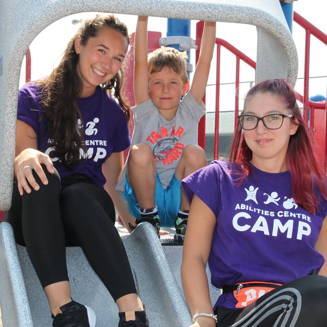 Camp counsellors with a participant on a slide.