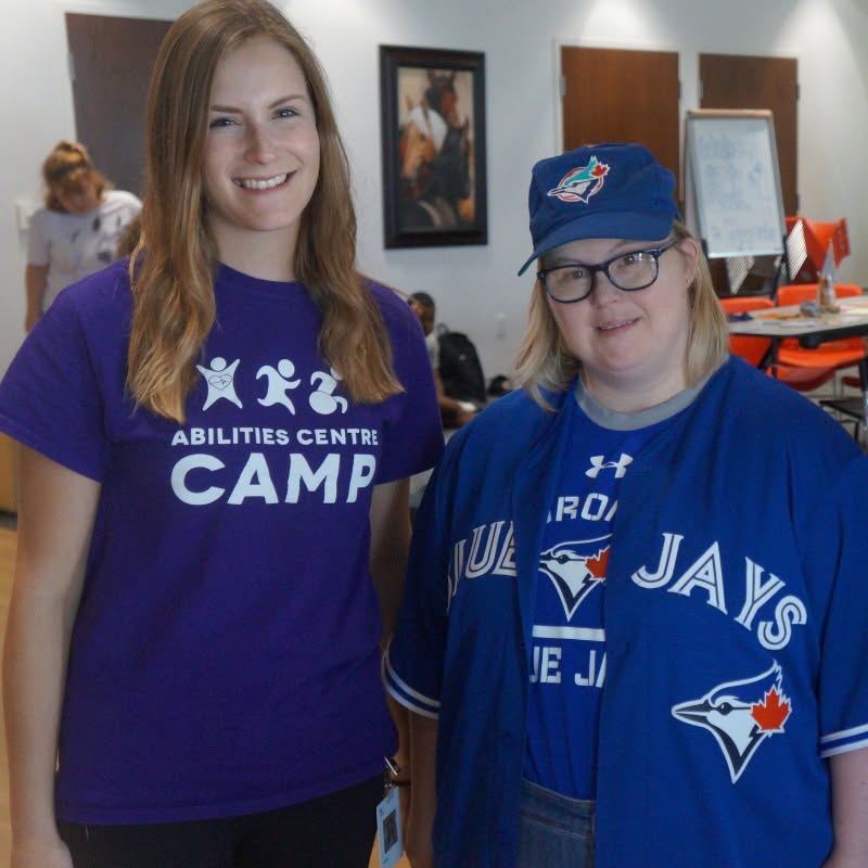 A camp counsellors with a participant who's wearing Toronto Blue Jays gear.