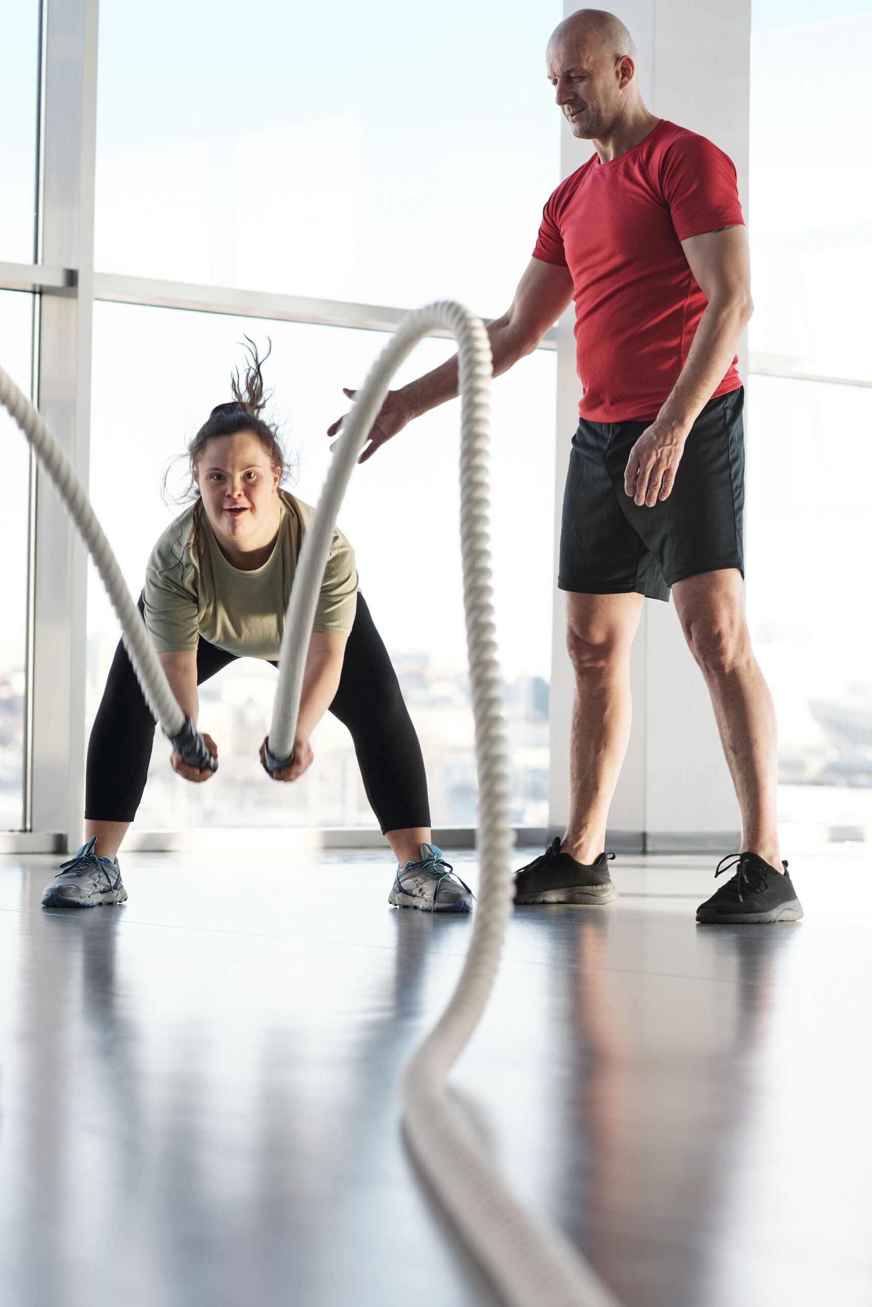 A trainer helping their client with cable ropes.