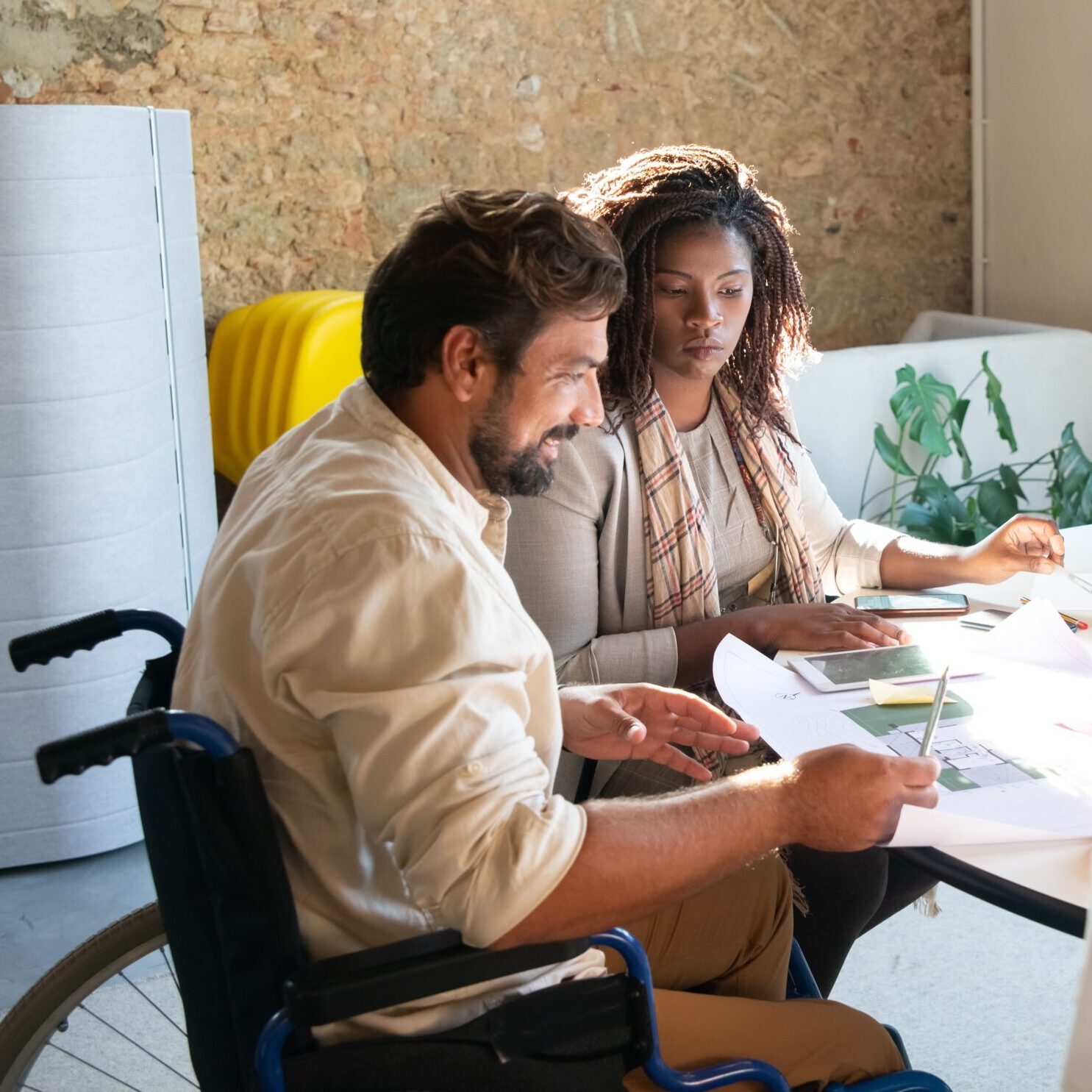 Two people sit at a desk looking at floorplans.
