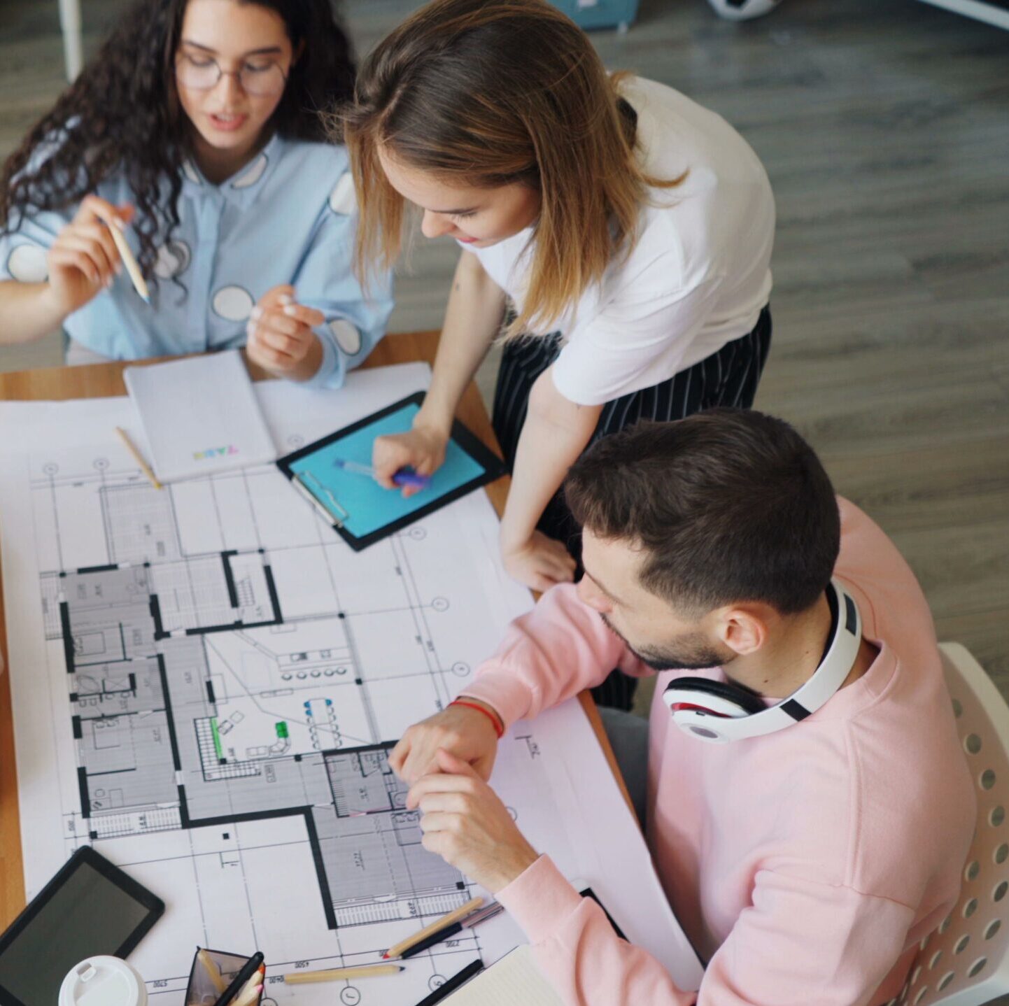 An overhead view of people working at a desk looking at floorplans.
