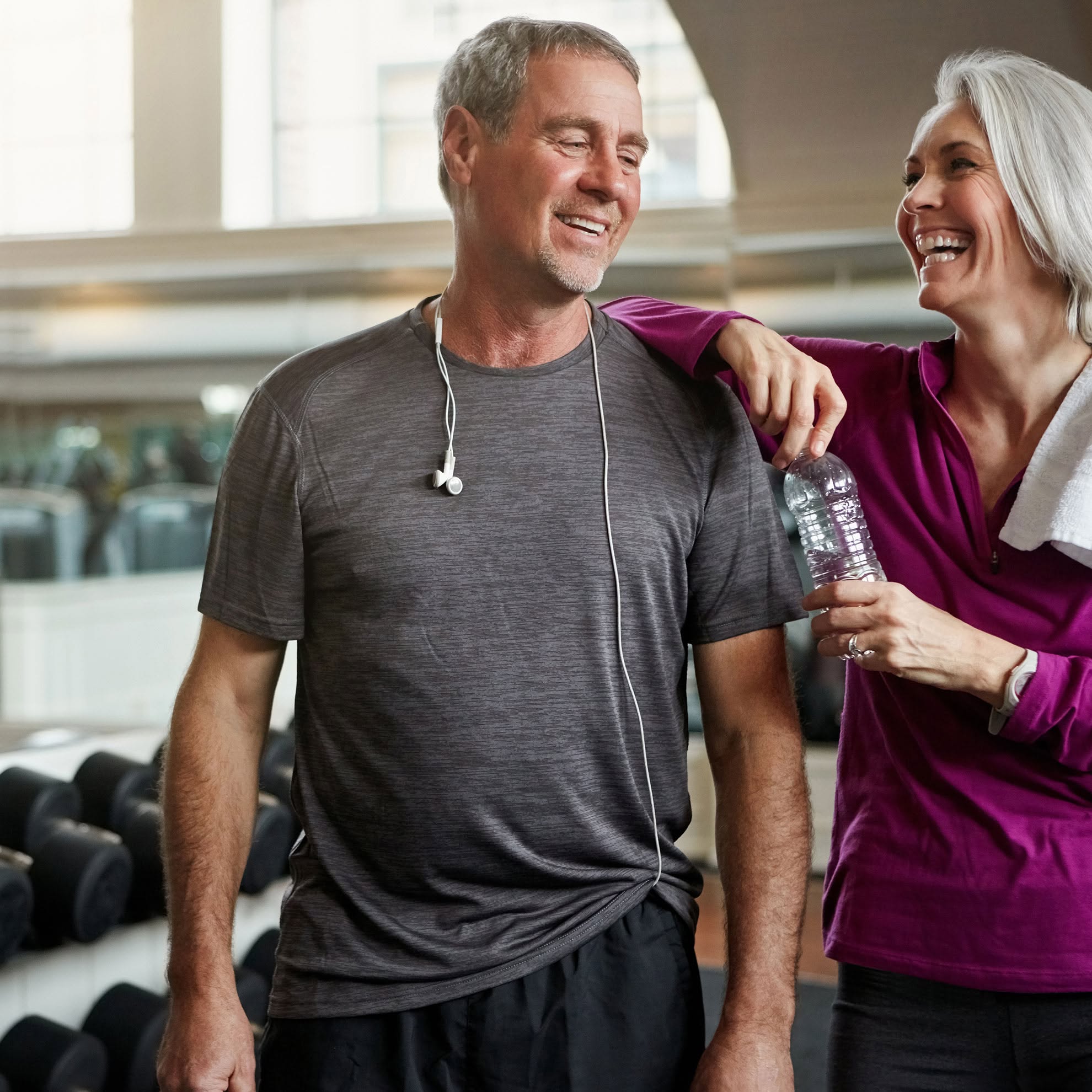 An older couple smile as after a rewarding fitness class.