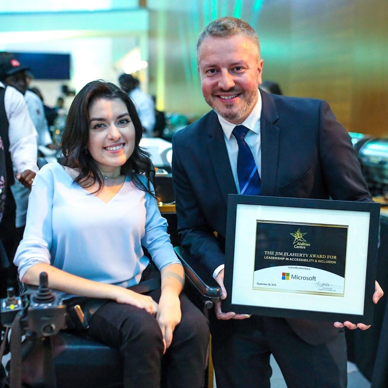 Maayan Ziv and a Microsoft representative pose together after Microsoft won the Jim Flaherty Award for Leadership and Inclusion at the Accessibility Awards.