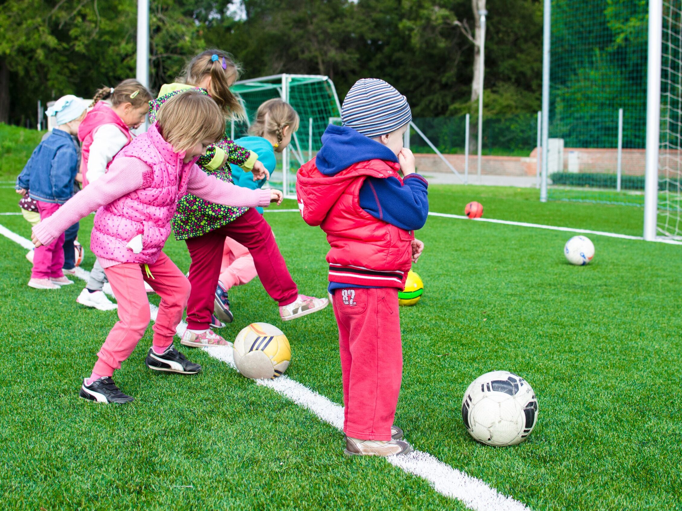 Little kids playing soccer on a soccer field.