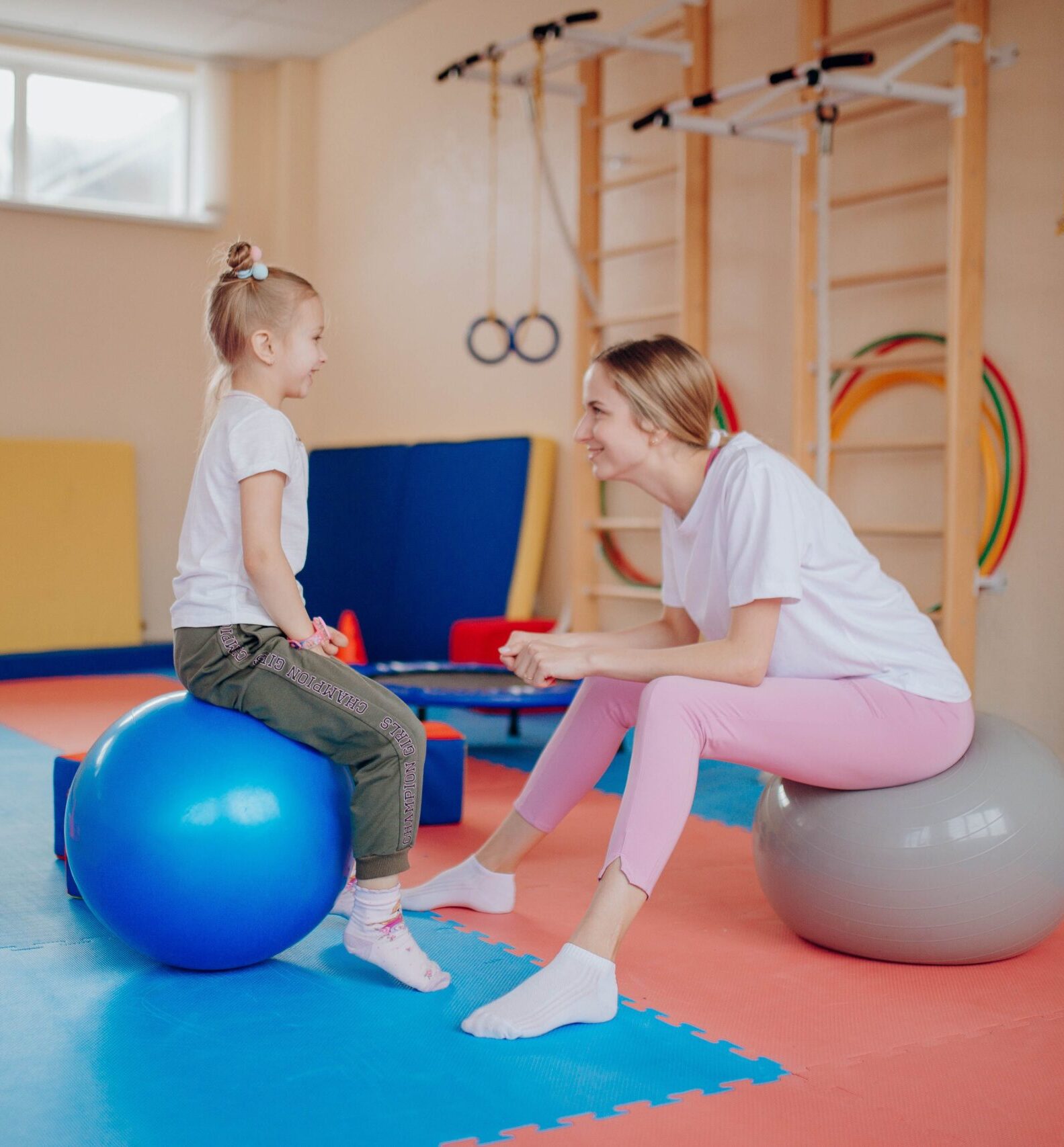 A woman and young girl sit on fitness balls as they gear up for a session.
