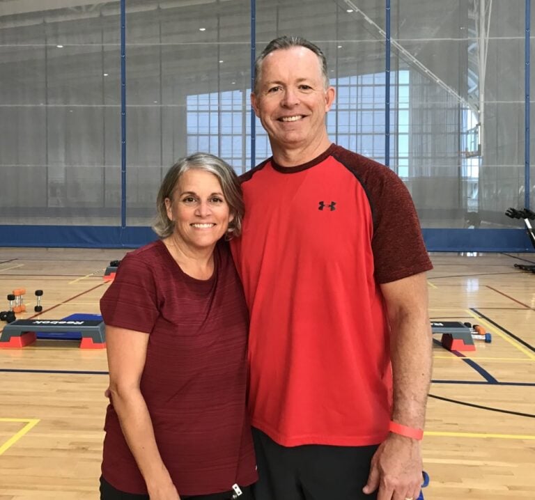 A couple smiles and poses on the court in the Jim Flaherty Field House.