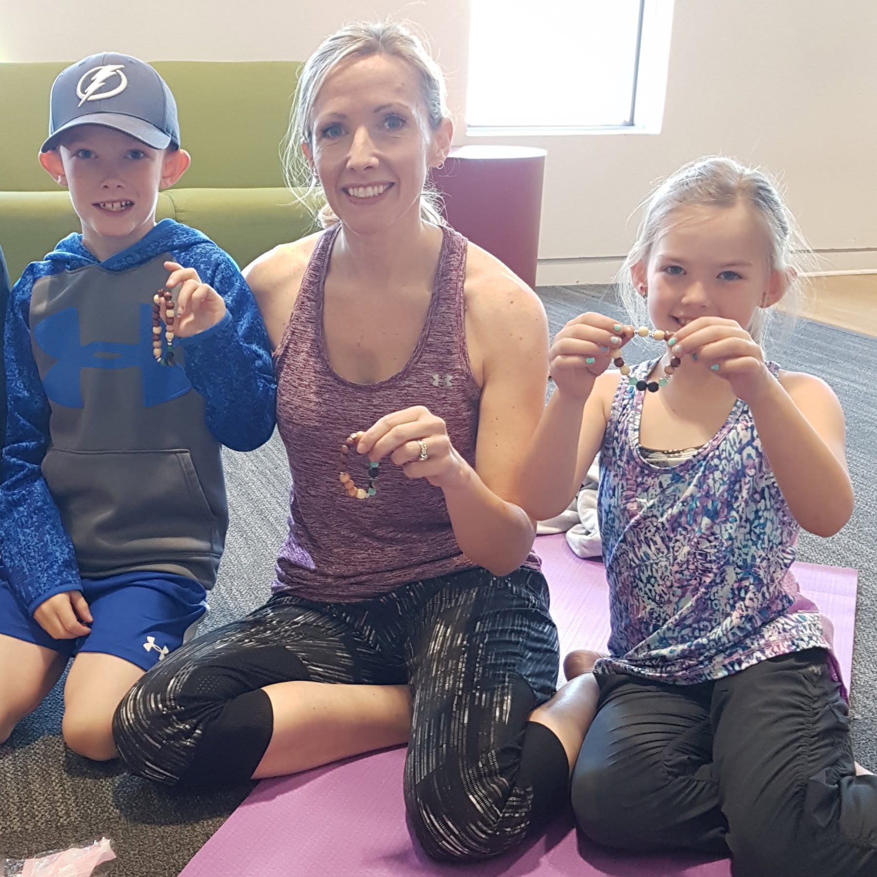 A woman and two children show off the bracelets they made.